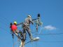 A low angle shot of electric linemen working on pole